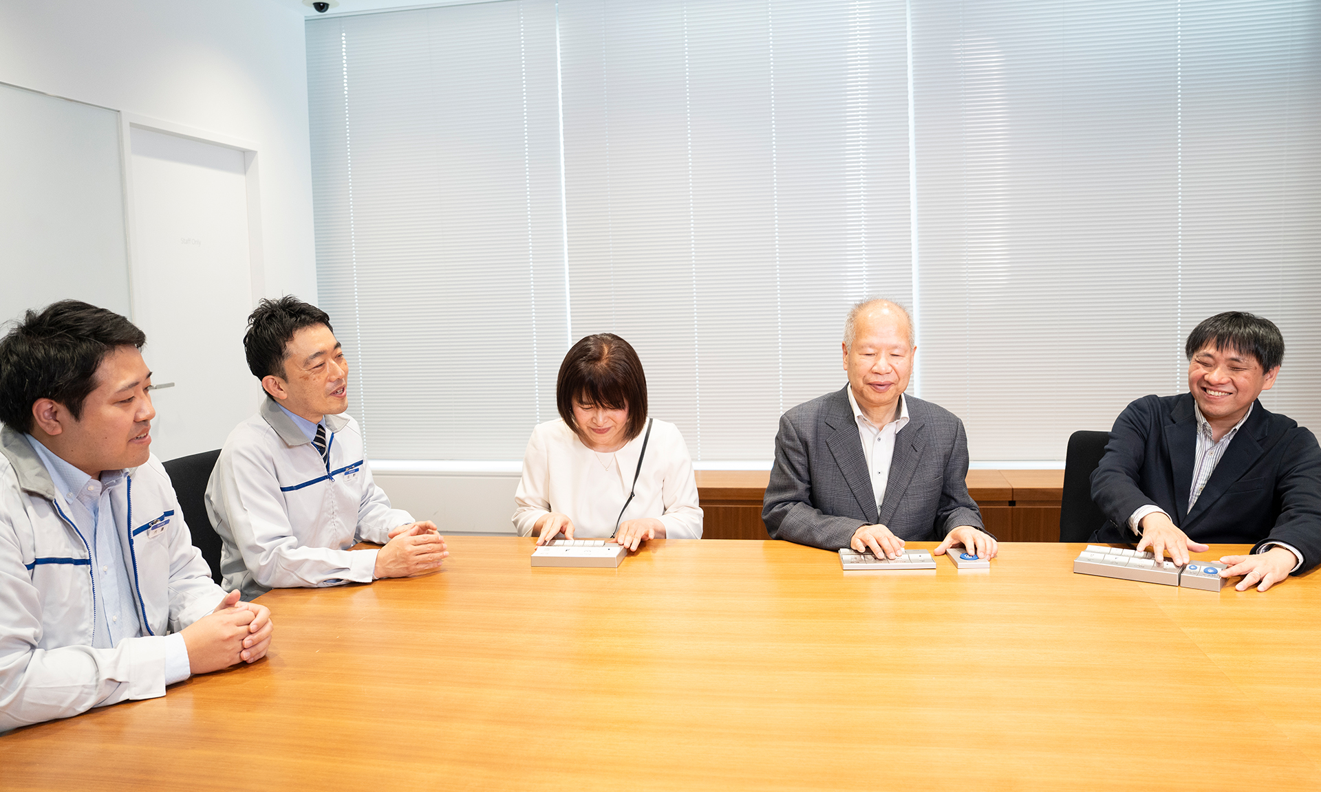 テーブルを囲んで座る5人。西島さん、長岡さん、大河内さんがリモコンを触っていて、その様子を内藤さんと北野さんが見つめている