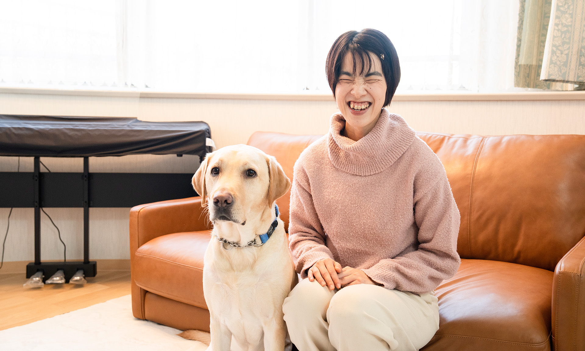 室内でソファに座ってにっこり微笑む鈴木さんとデイズくん